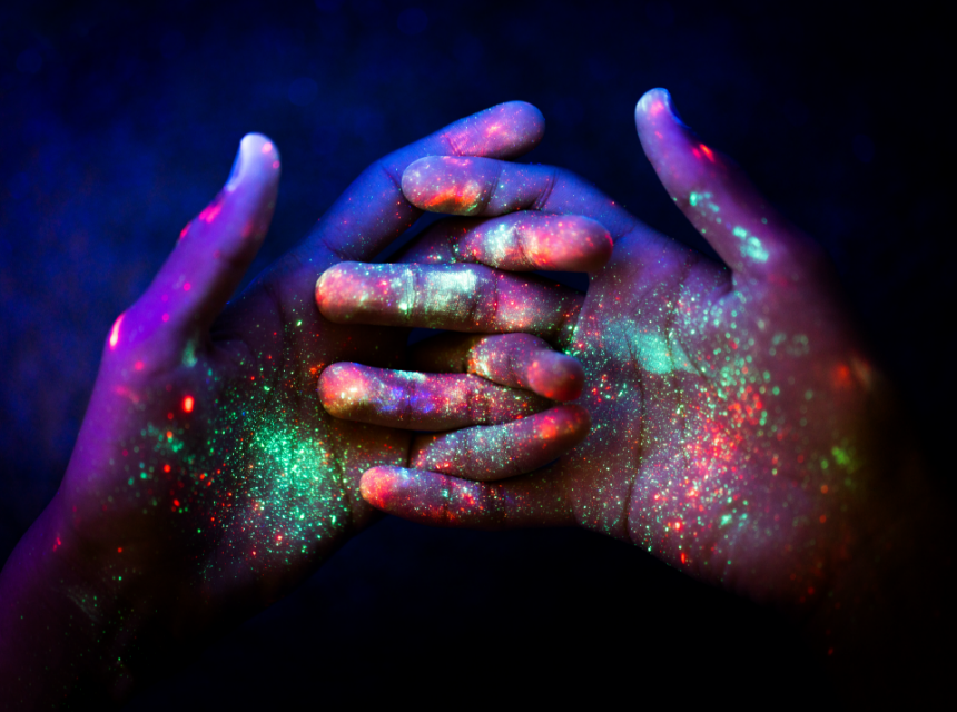 Ineinander verschlungene Hände die mit Fluoreszierende Schwarzlicht Farbe bedeckt sind