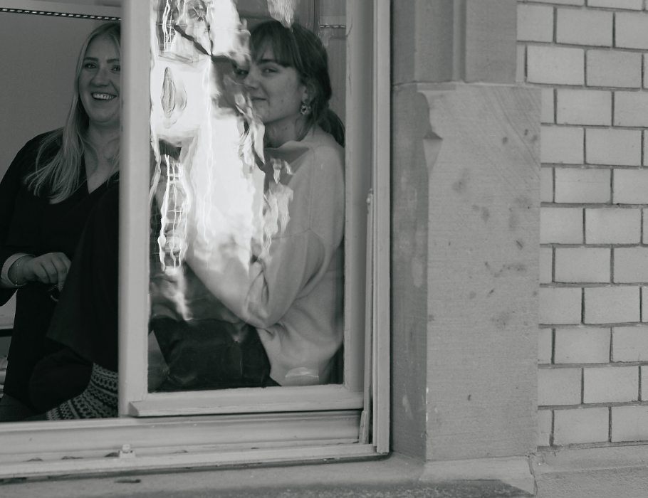 Schnappschuss durch ein Fenster auf zwei lachende Mitarbeiterinnen